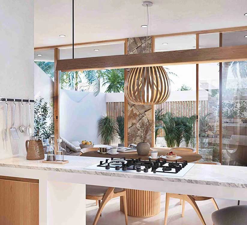 Modern open kitchen island with marble countertop, integrated gas stove, slatted pendant lighting, round dining table, and floor-to-ceiling glass patio doors at The Novéra Beyond luxury villa in Uluwatu, Bali.