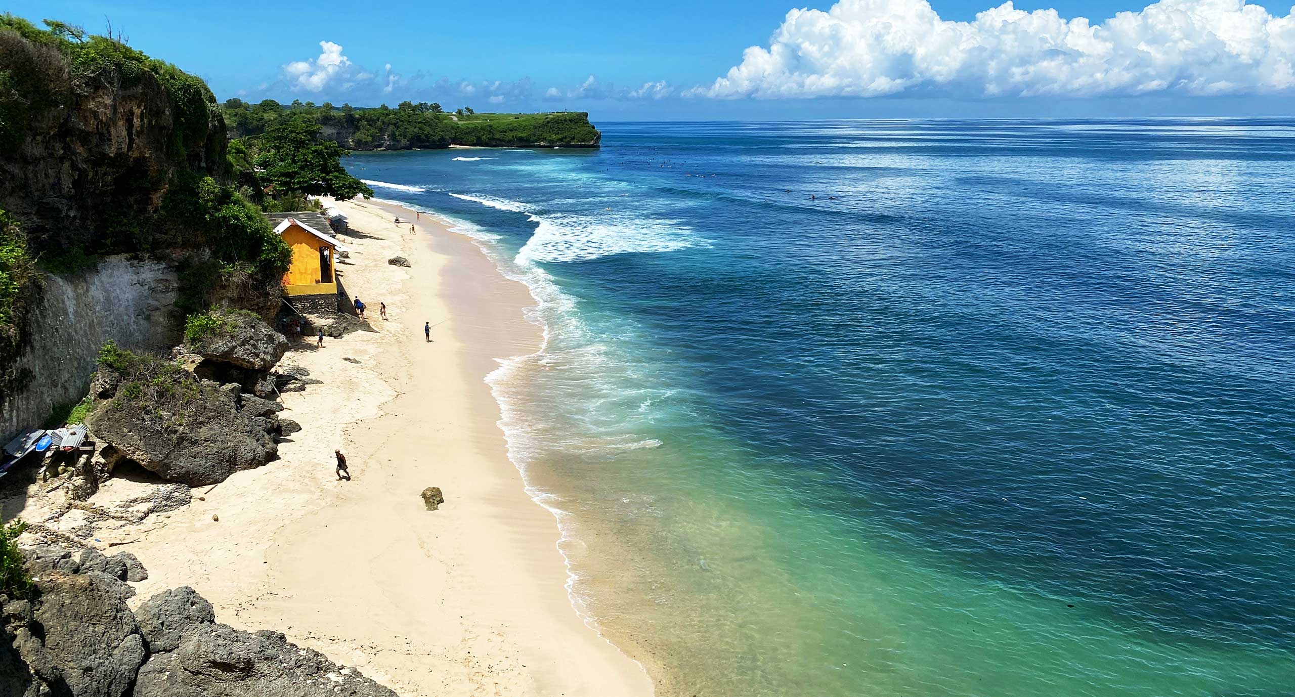 Scenic aerial view of white sand beach, turquoise water, and limestone cliffs along the Uluwatu coastline near The Novéra Beyond luxury villa in Bali